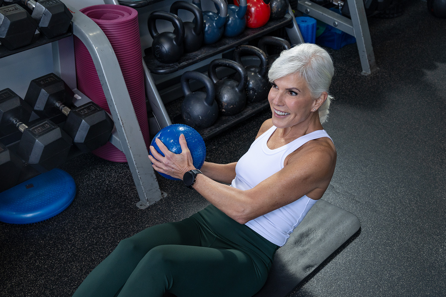 Fitness Together trainer and client sharing a motivating hand-clap moment during a squat — the 'We're In This Together' promise in action